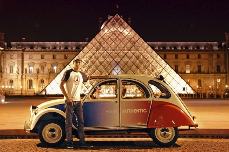 2CV Citroën cocorico delante de la Pirámide del Louvre de noche